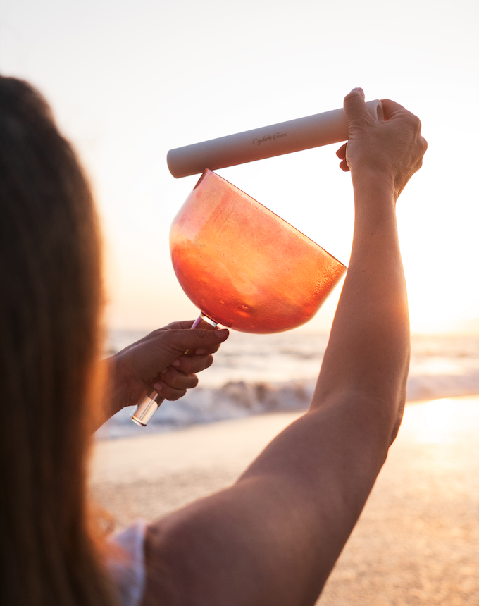 Amanda holding a crystal singing bowl at the beach