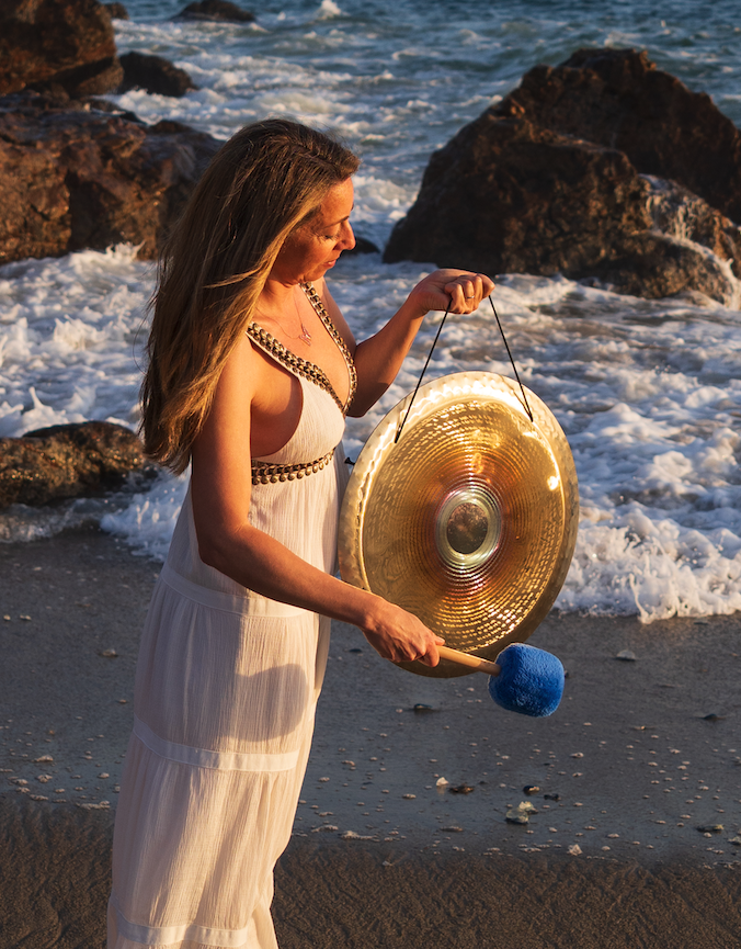 Amanda holding a gong by the ocean for a private sound healing event